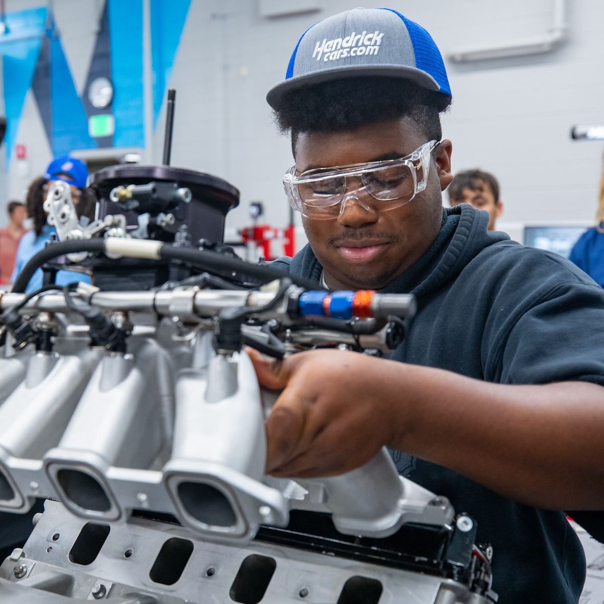  An early college student works with an automobile engine
